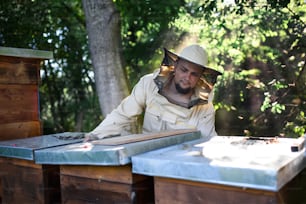 Front view portrait of man beekeeper working in apiary.