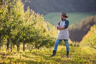 A mature farmer standing outdoors in orchard. A copy space.