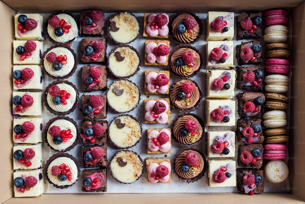A selection of colorful and delicious cake desserts in box on table.