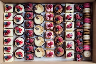 A selection of colorful and delicious cake desserts in box on table.