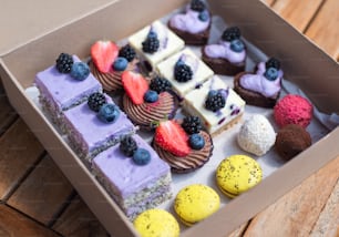 Uma seleção de sobremesas de bolo coloridas e deliciosas em caixa na mesa.