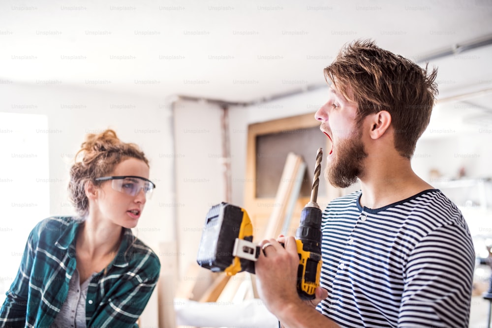 Small business of a young couple. Man and woman worker with an electric drill in the carpenter workroom.