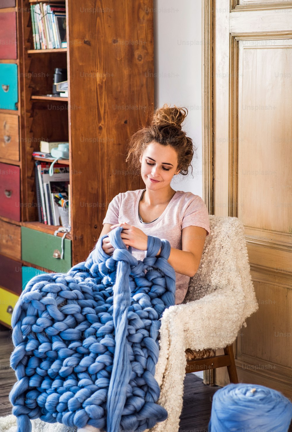若い女性の中小企業。ウールの毛布を手編みする若い女性。