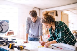 Small business of a young couple. Man and woman worker in the carpenter workroom.