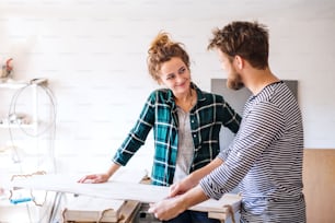 Pequeno negócio de um jovem casal. Homem e mulher operários na sala de trabalho do carpinteiro.