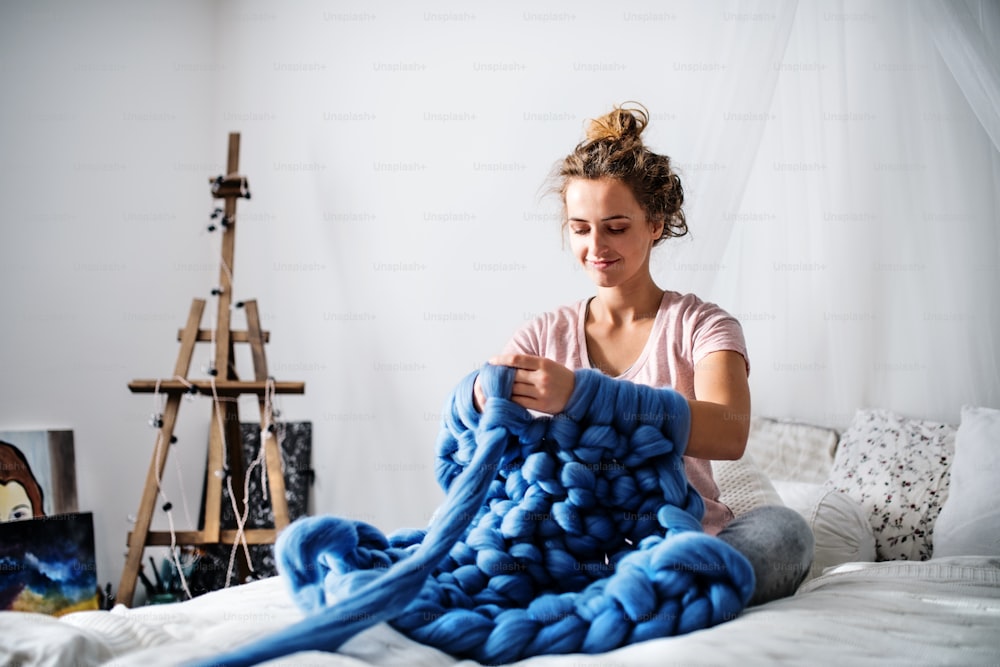 Piccola impresa di una giovane donna. Giovane donna che lavora a maglia una coperta wollen.