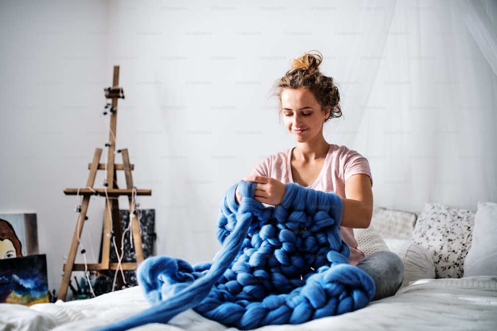 Small business of a young woman. Young woman hand-knitting a wollen blanket.