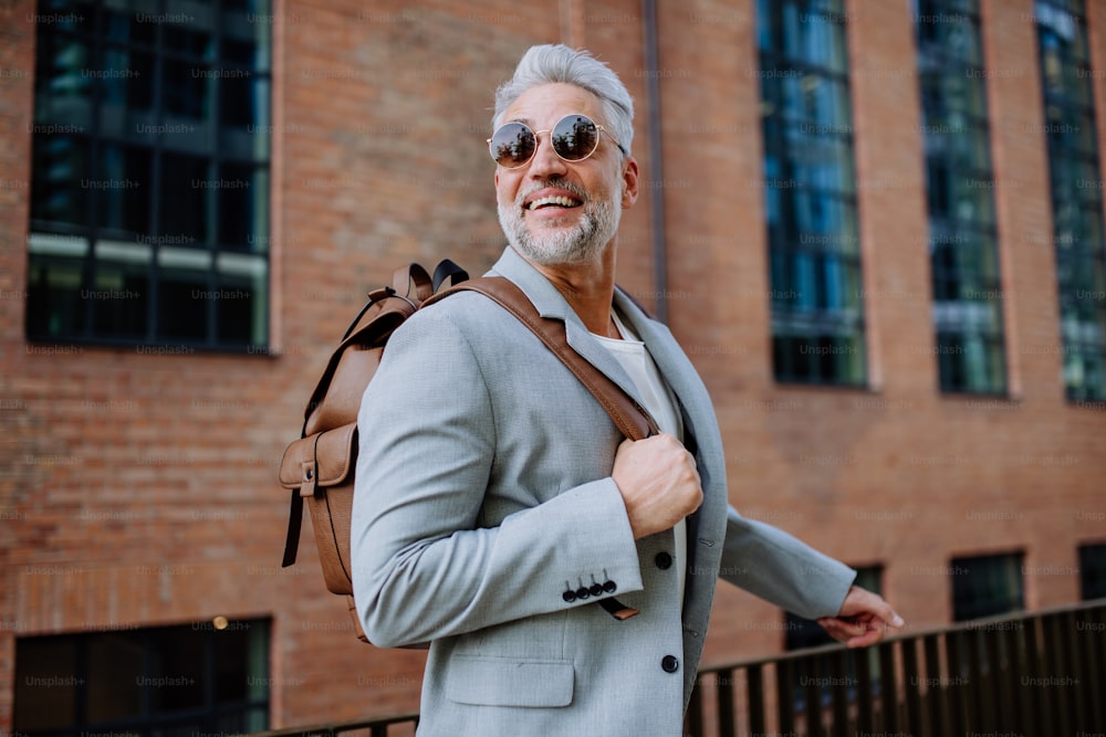 バックパックを背負った自信に満ちた男が通りを歩き、夏にカジュアルな服を着たビジネスマンが通勤途中。