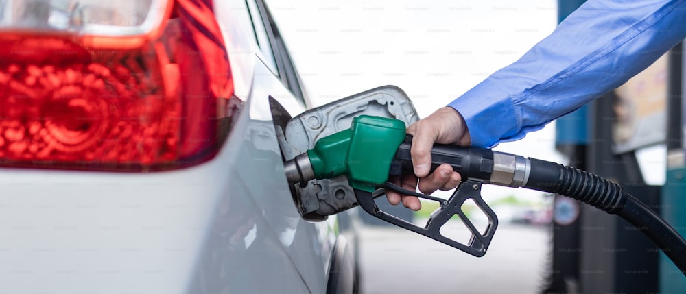 A hand refilling the car with fuel at the refuel station