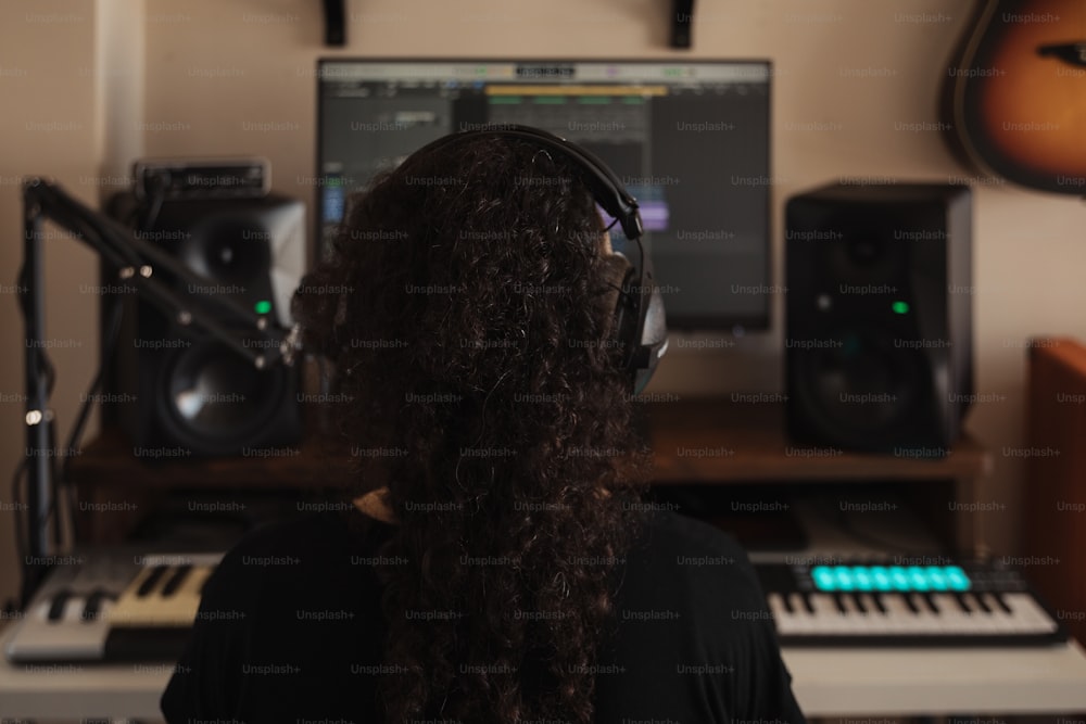 a woman wearing headphones sitting in front of a keyboard