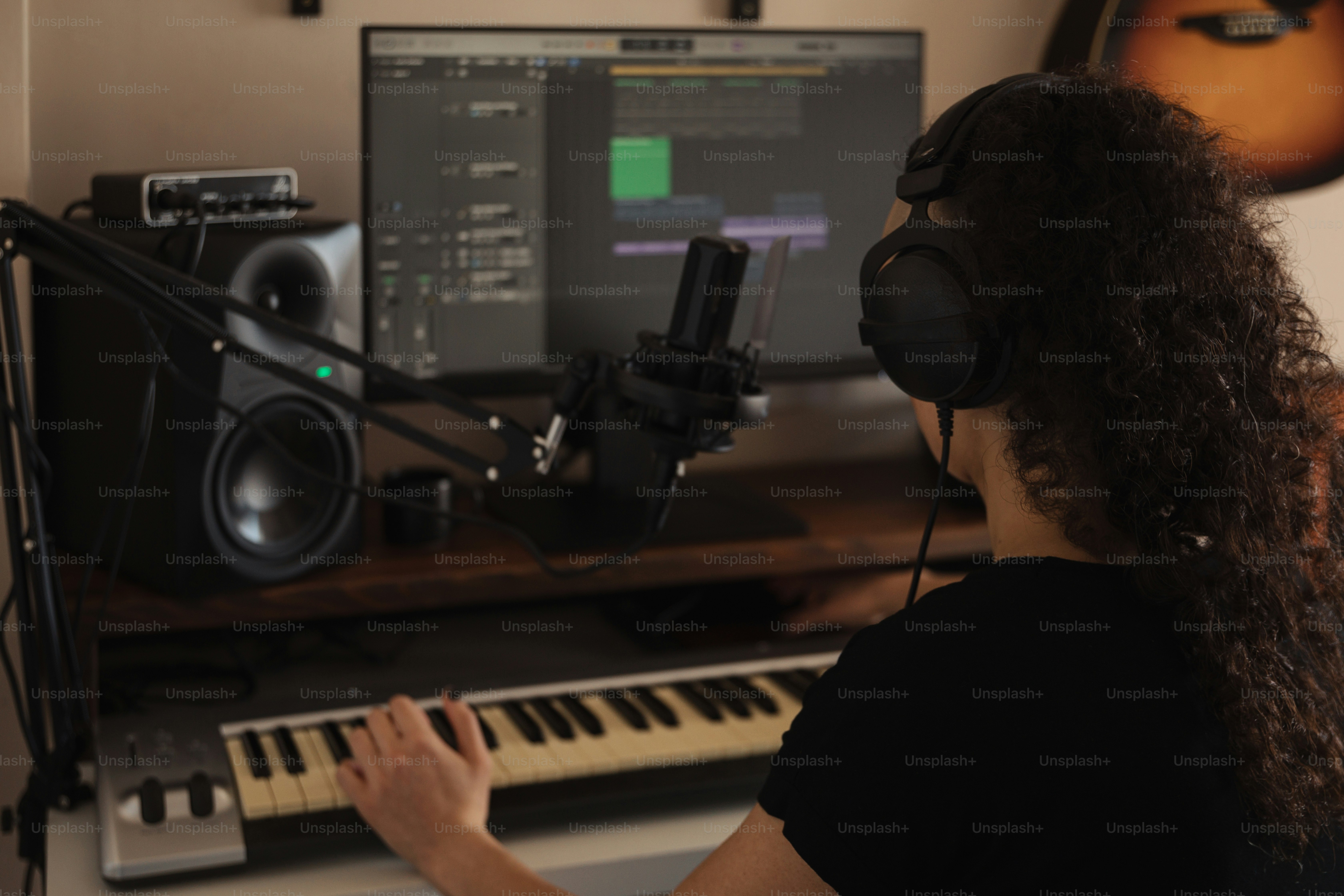 a woman wearing headphones sitting in front of a keyboard