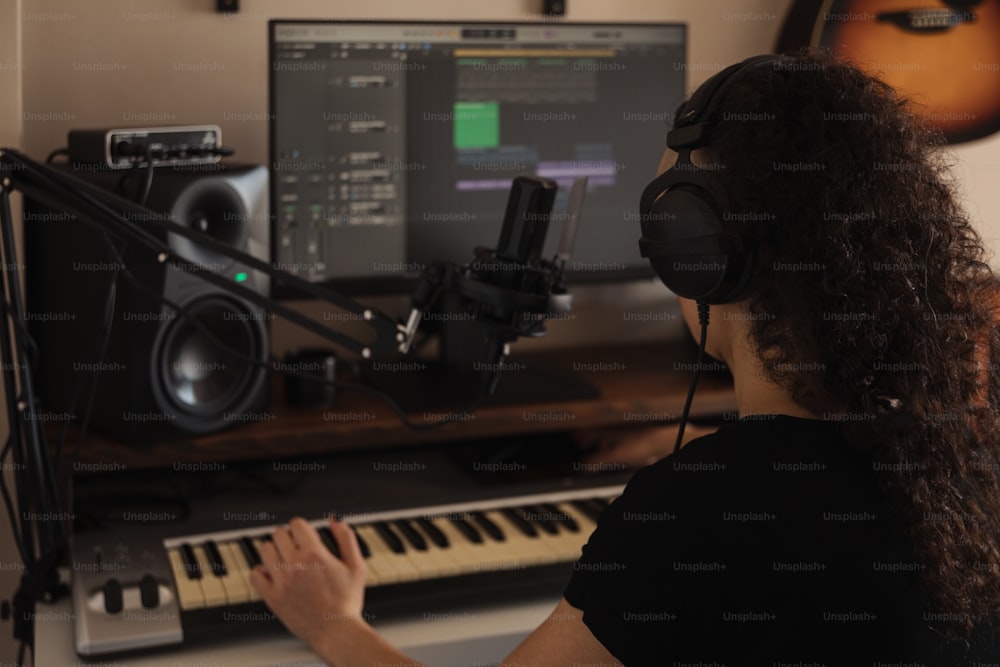 a woman wearing headphones sitting in front of a keyboard