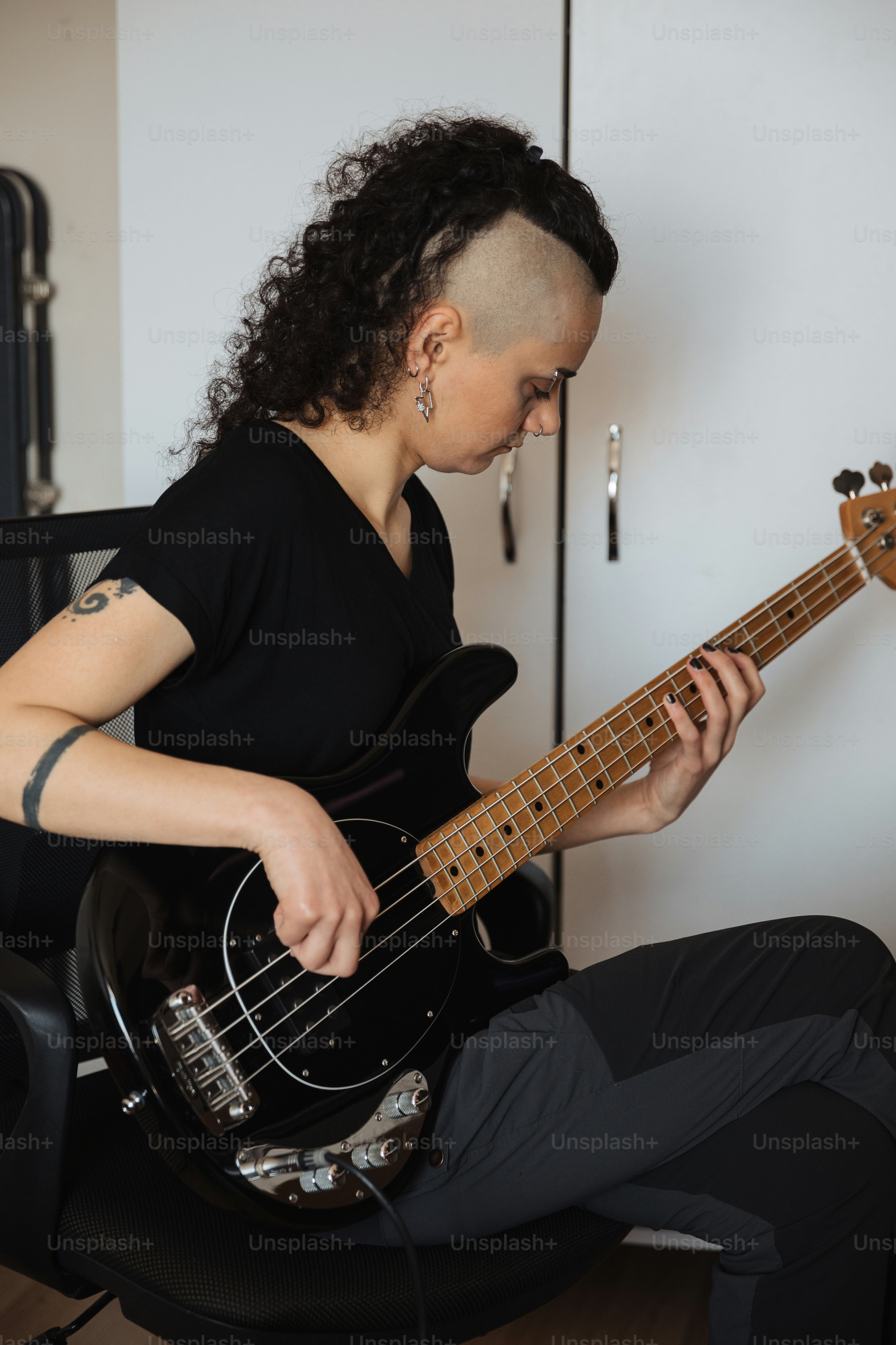 a woman sitting on a chair playing a bass guitar