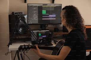 a woman playing a guitar in front of a computer