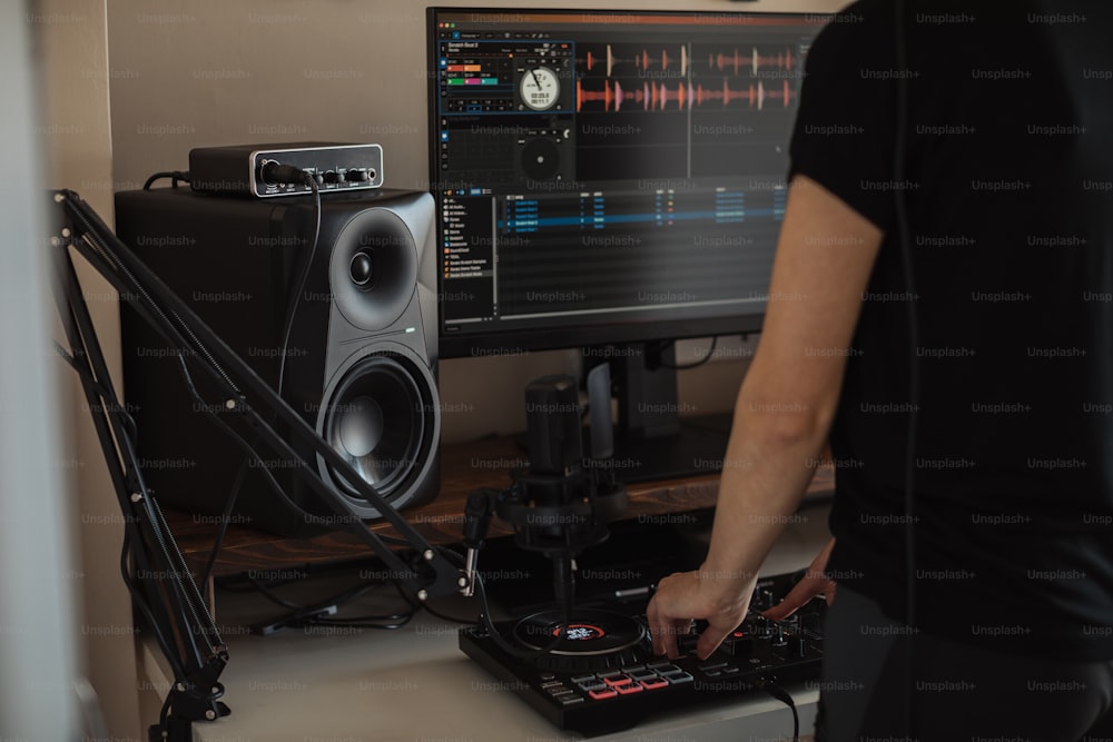 Eine Person, die mit einem DJ-Mixer vor einem Computer steht