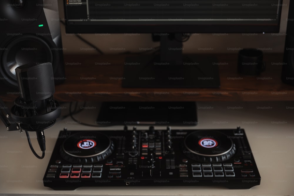 Un controller DJ seduto sopra un tavolo accanto a un monitor