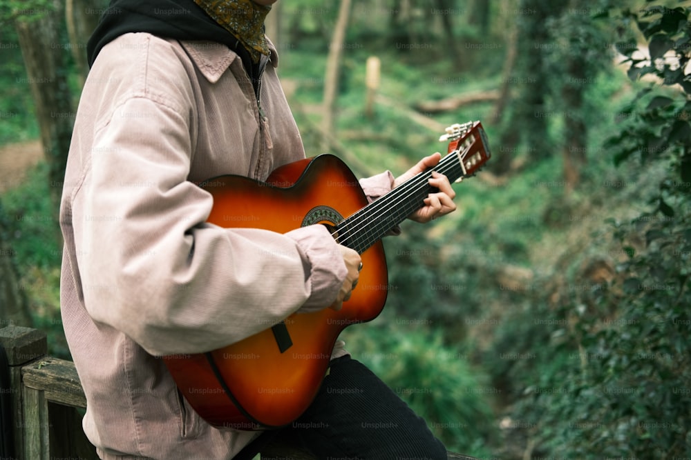 um homem sentado em um banco tocando uma guitarra