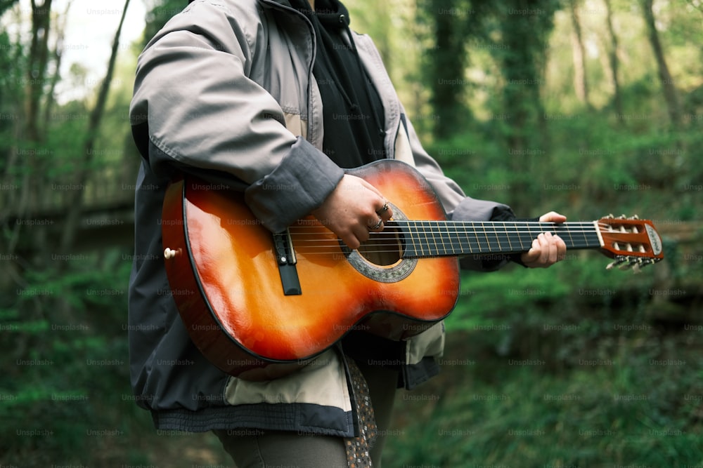 a man is playing a guitar in the woods