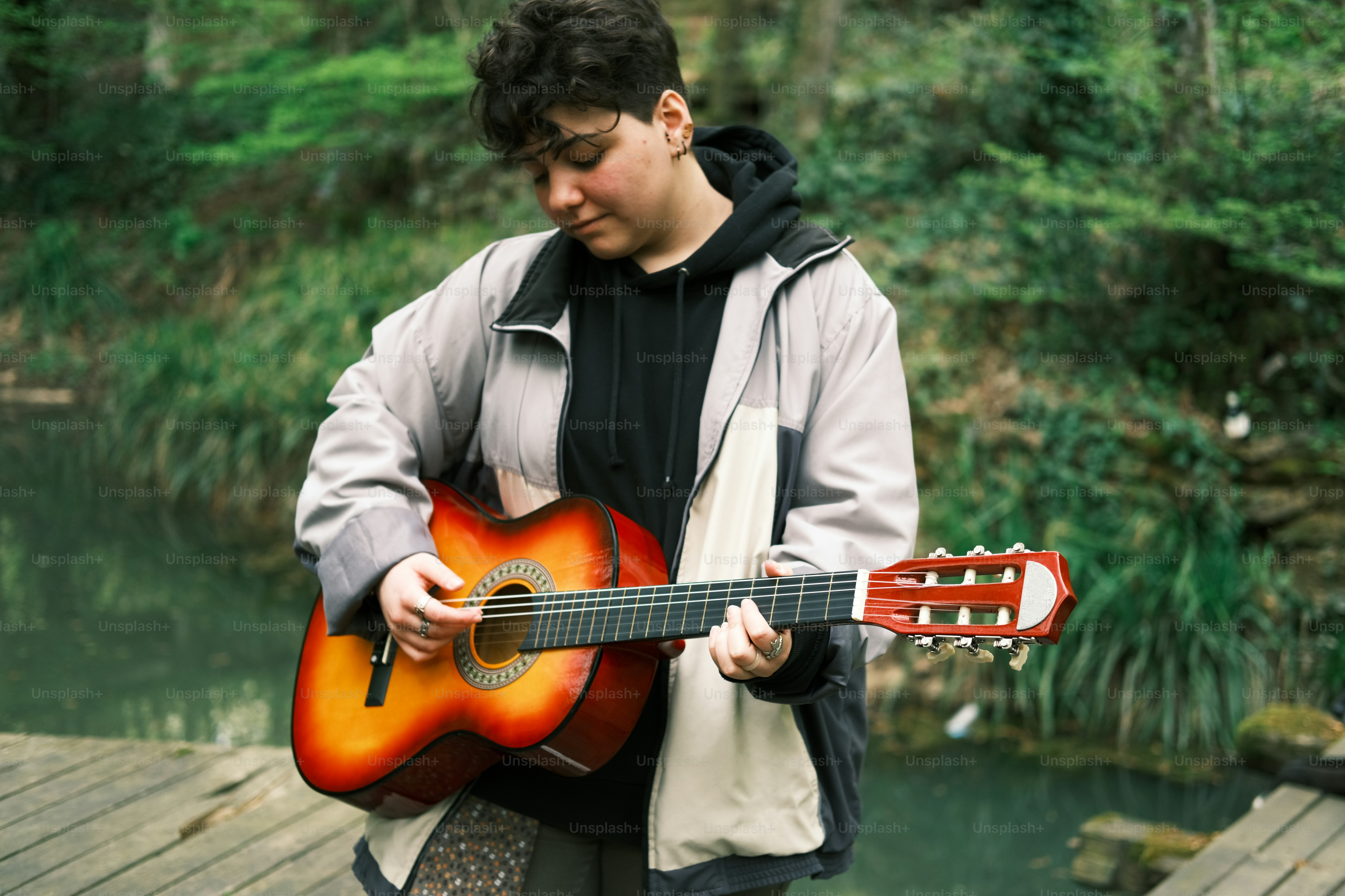 a man holding a guitar on a wooden bridge