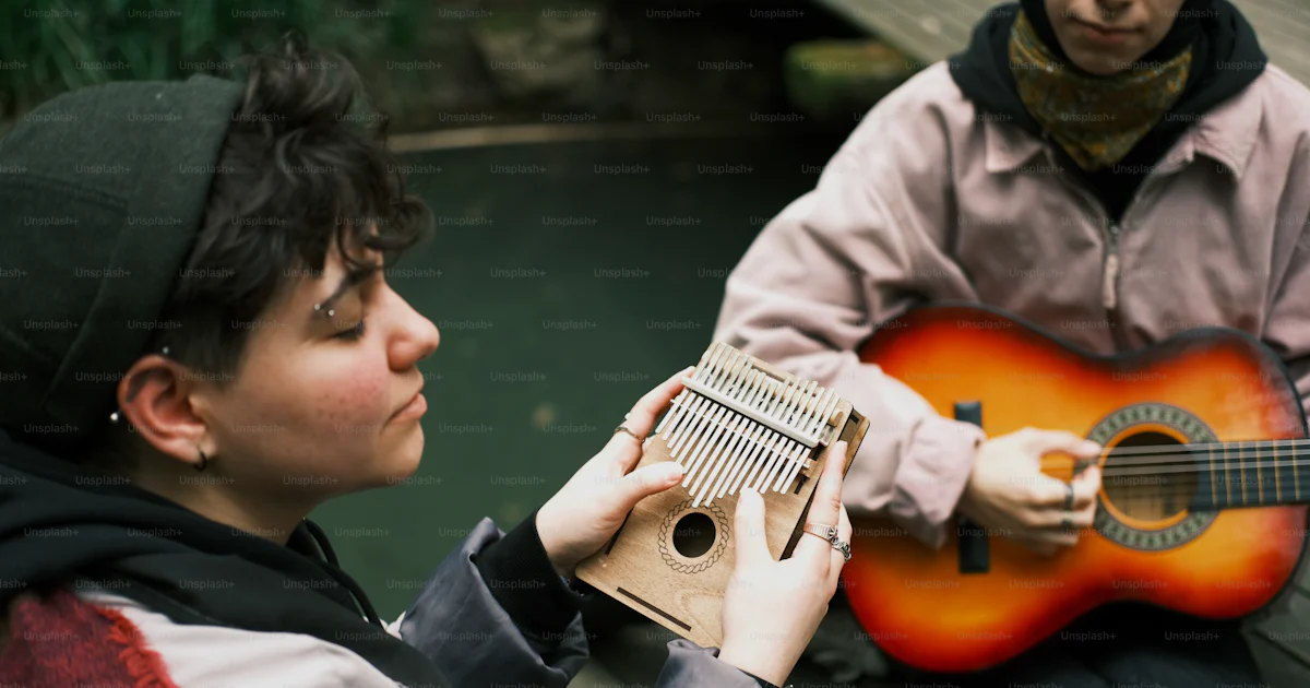 Two Person Instrument Two people sitting on a dock playing a musical instrument photo ...