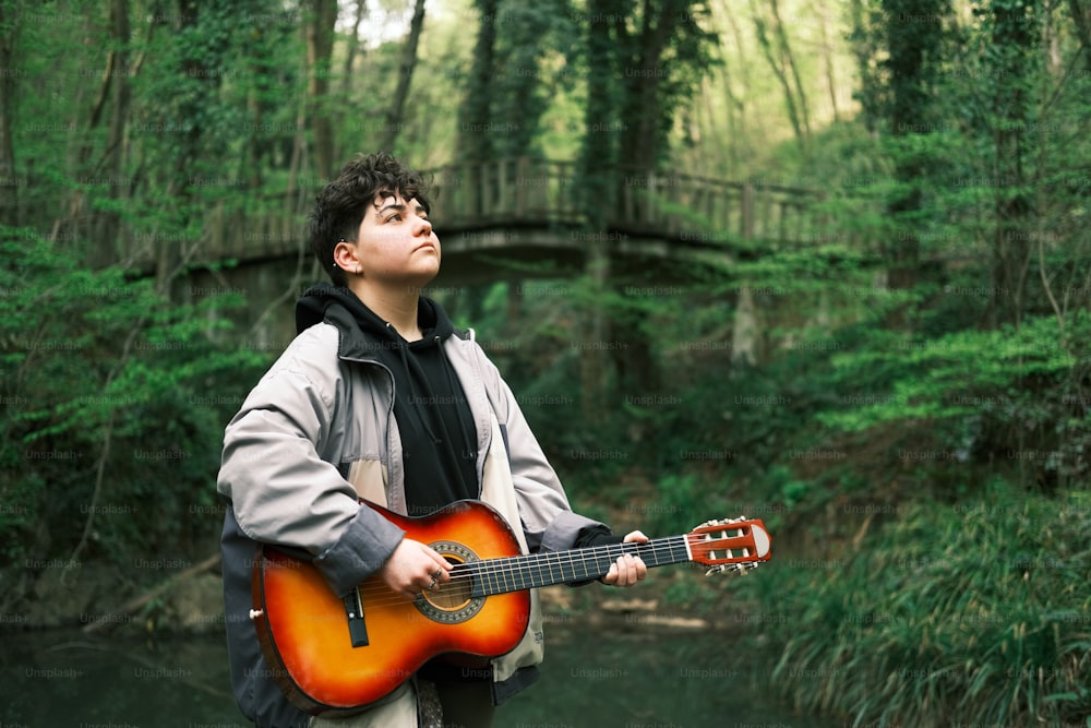 Un uomo in piedi in una foresta con una chitarra in mano