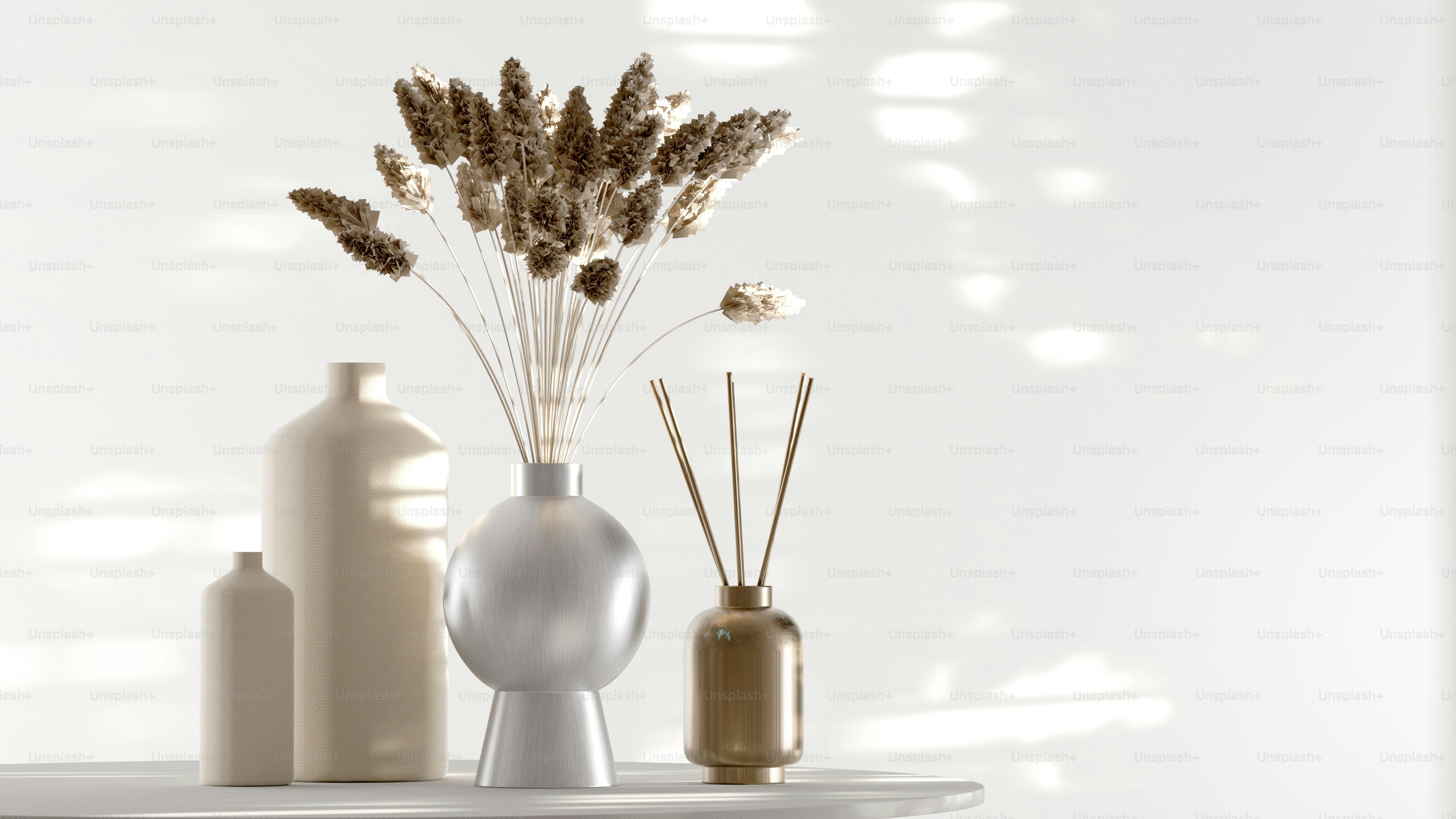 three vases with flowers and reeds on a table