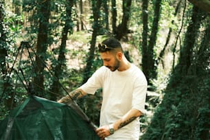 a man holding a green tarp in the woods