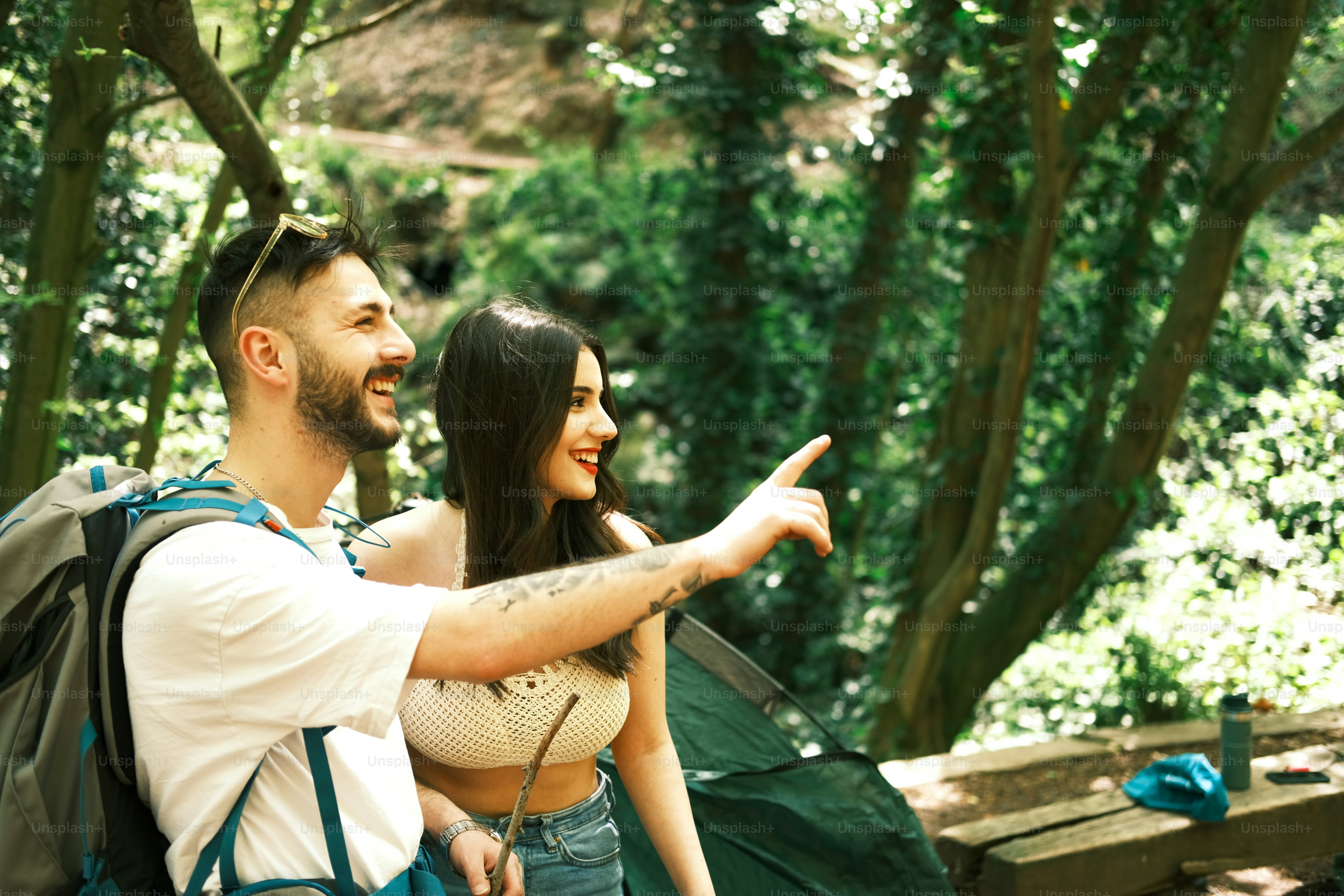 a man and a woman standing in the woods pointing at something