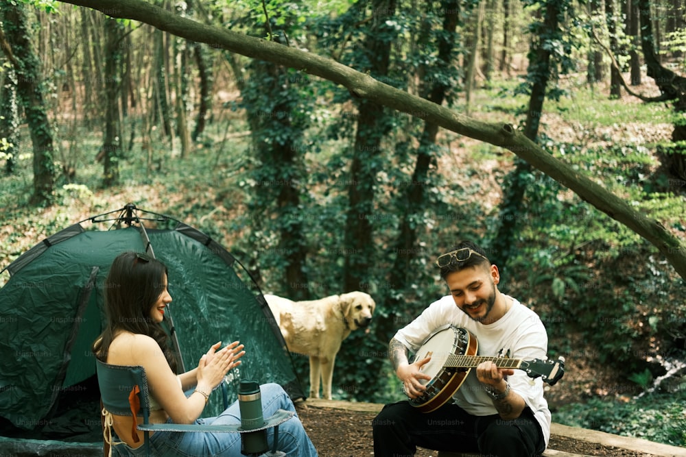 a man and a woman playing guitar in the woods