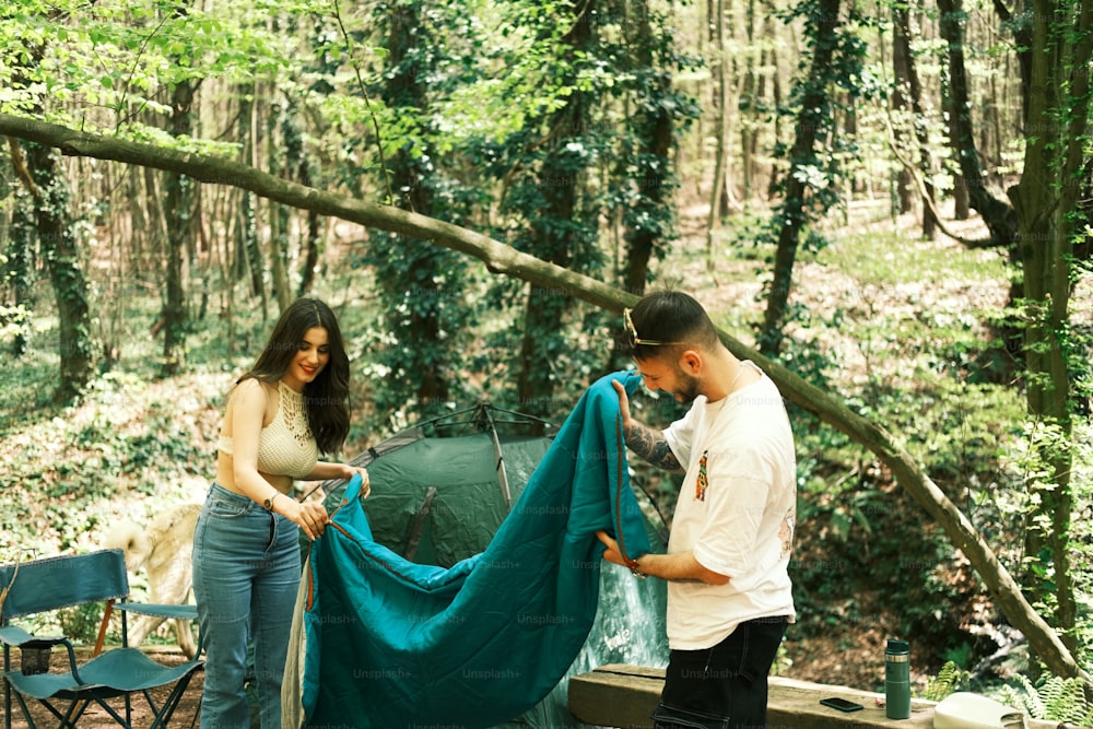 Un uomo e una donna in piedi accanto a una tenda nel bosco