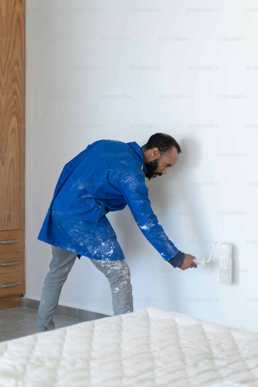 um homem pintando uma parede com um rolo de tinta