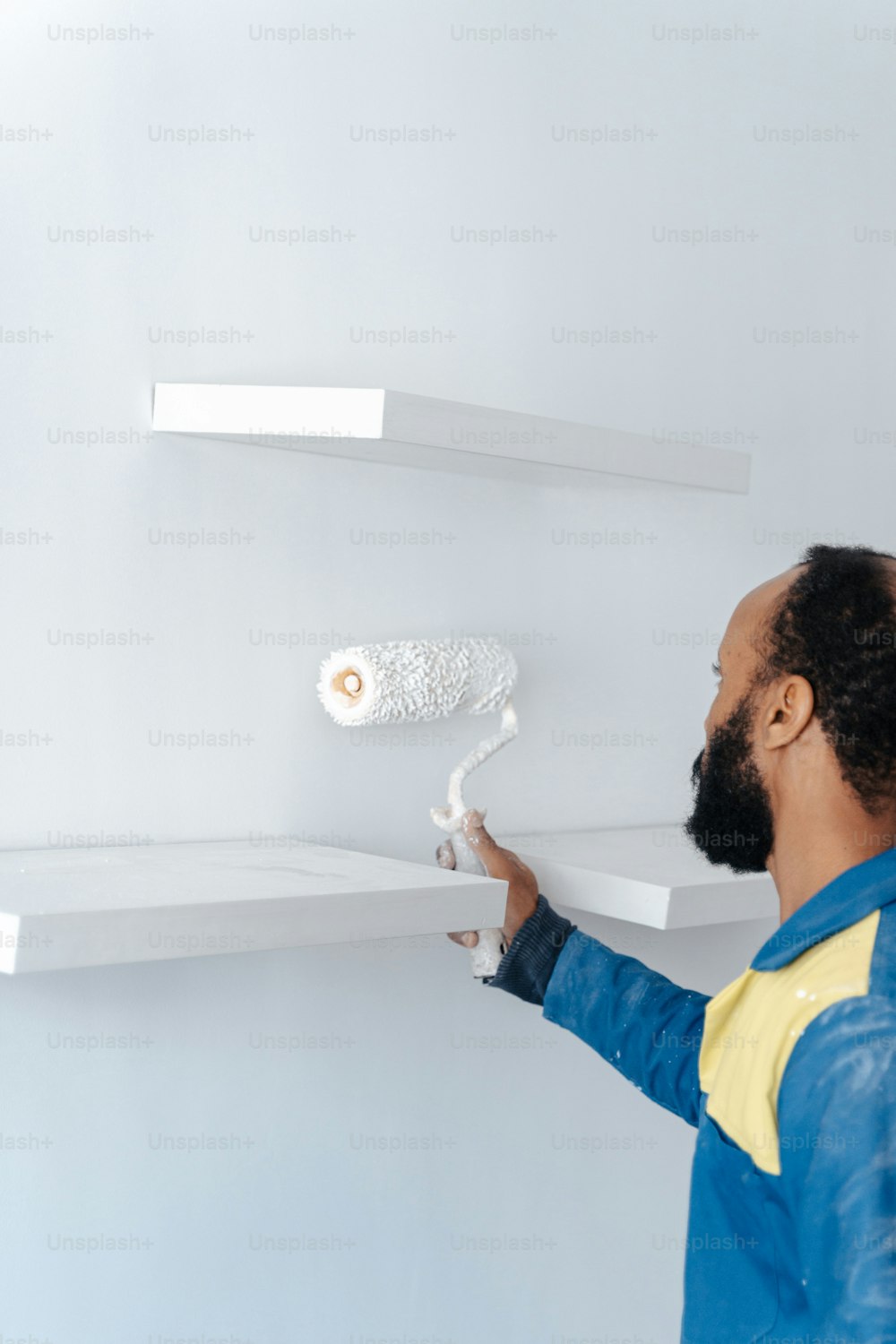 a man is painting a shelf with white paint