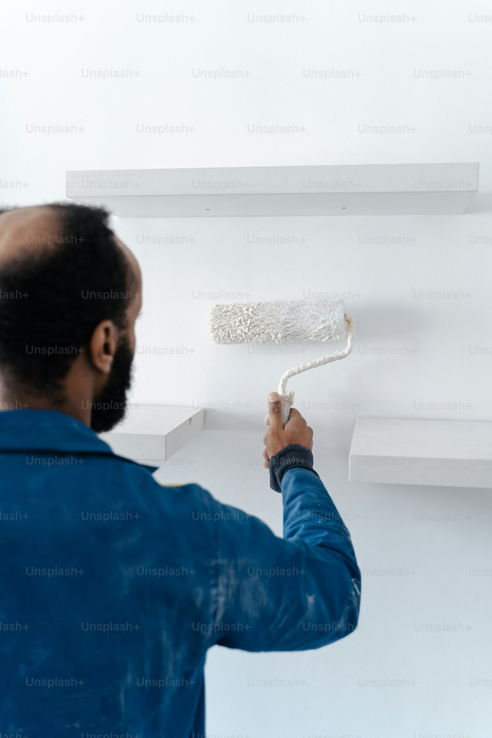 um homem pintando uma parede com tinta branca
