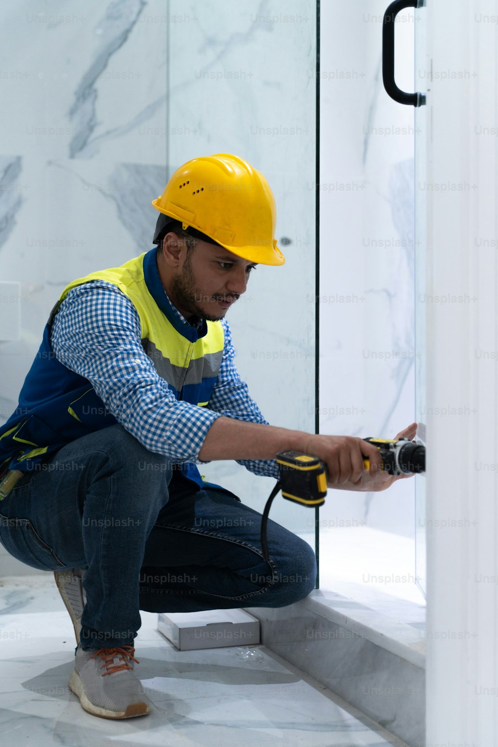 a man wearing a hard hat and holding a drill