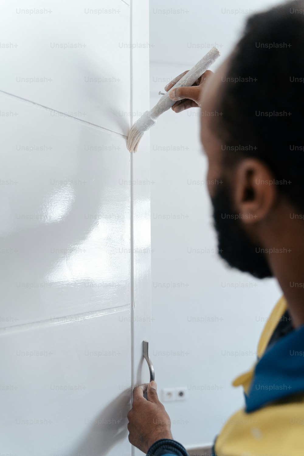 한 남자가 하얀 페인트로 벽을 칠하고 있다