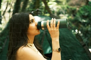 a woman drinking out of a green cup