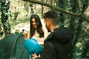 a man and a woman setting up a tent in the woods