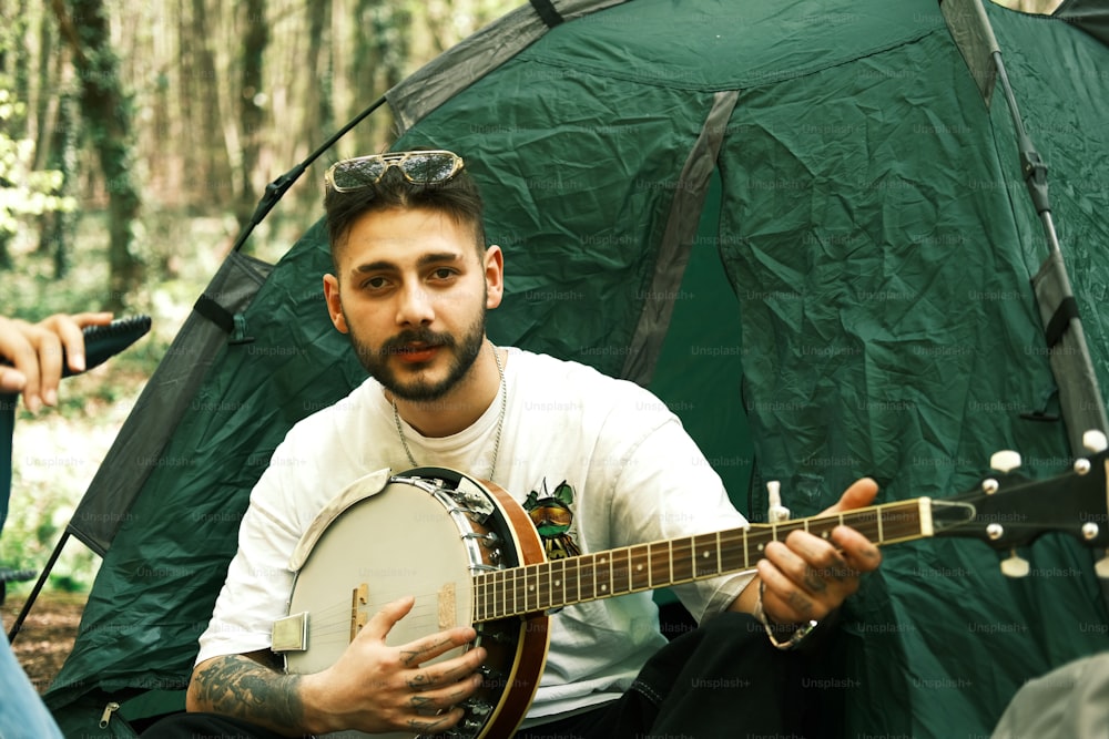 Un uomo seduto davanti a una tenda che tiene una chitarra