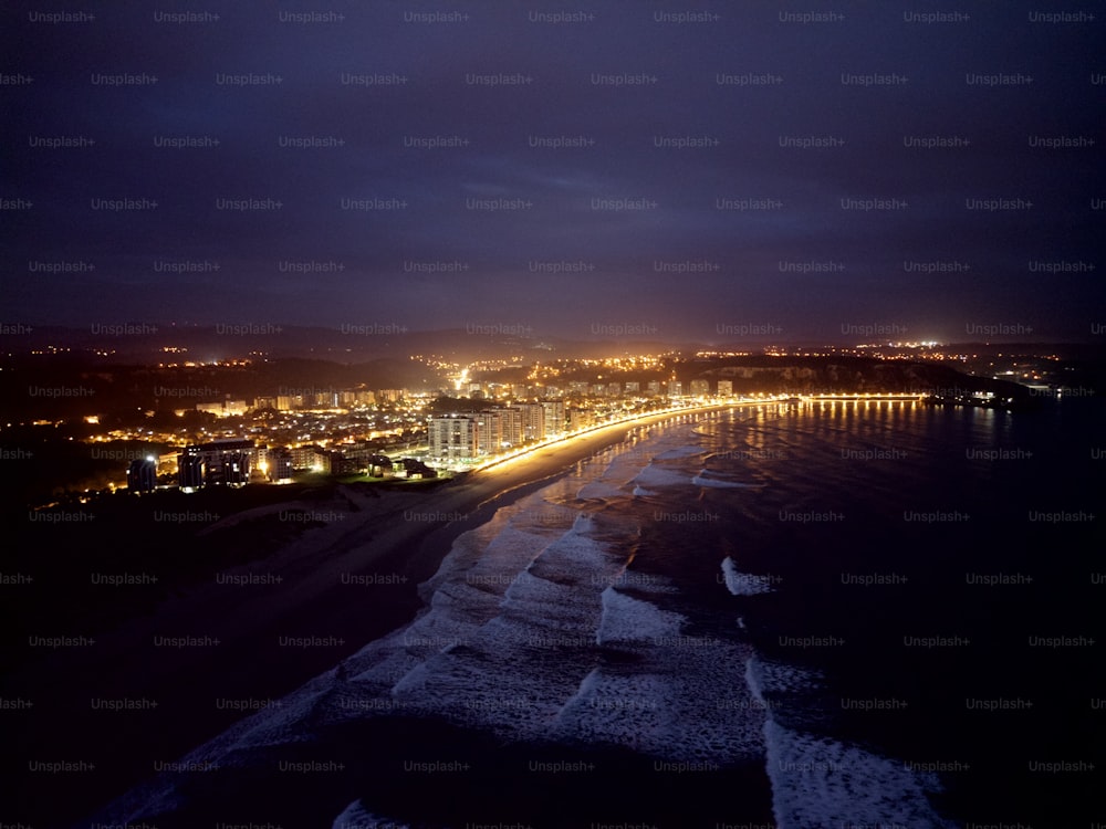 uma vista noturna de uma praia e luzes da cidade
