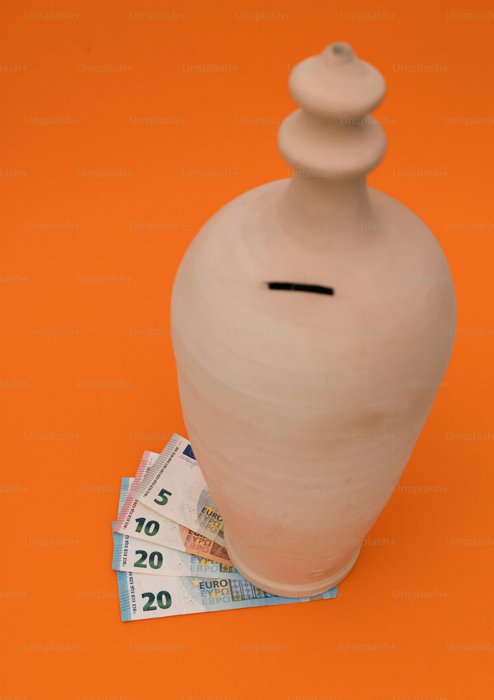 a white vase sitting on top of a pile of money
