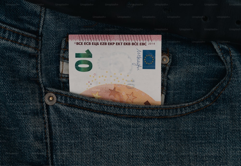 Un billete de dinero que sobresale del bolsillo trasero de un par de jeans