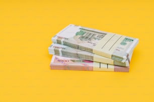 Una pila de dinero encima de una mesa amarilla