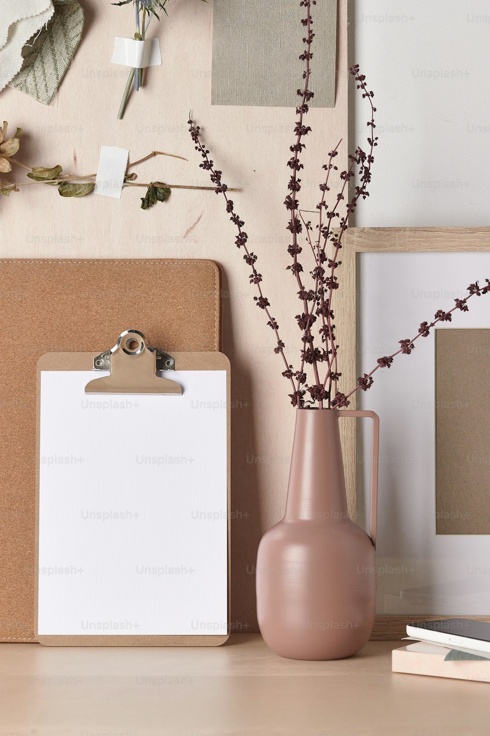 Un vaso rosa con fiori accanto a un blocco appunti
