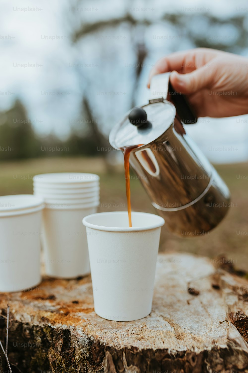 une personne verse une tasse de café d’une cafetière