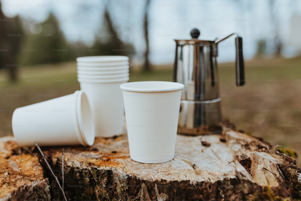 a stack of white cups sitting on top of a tree stump
