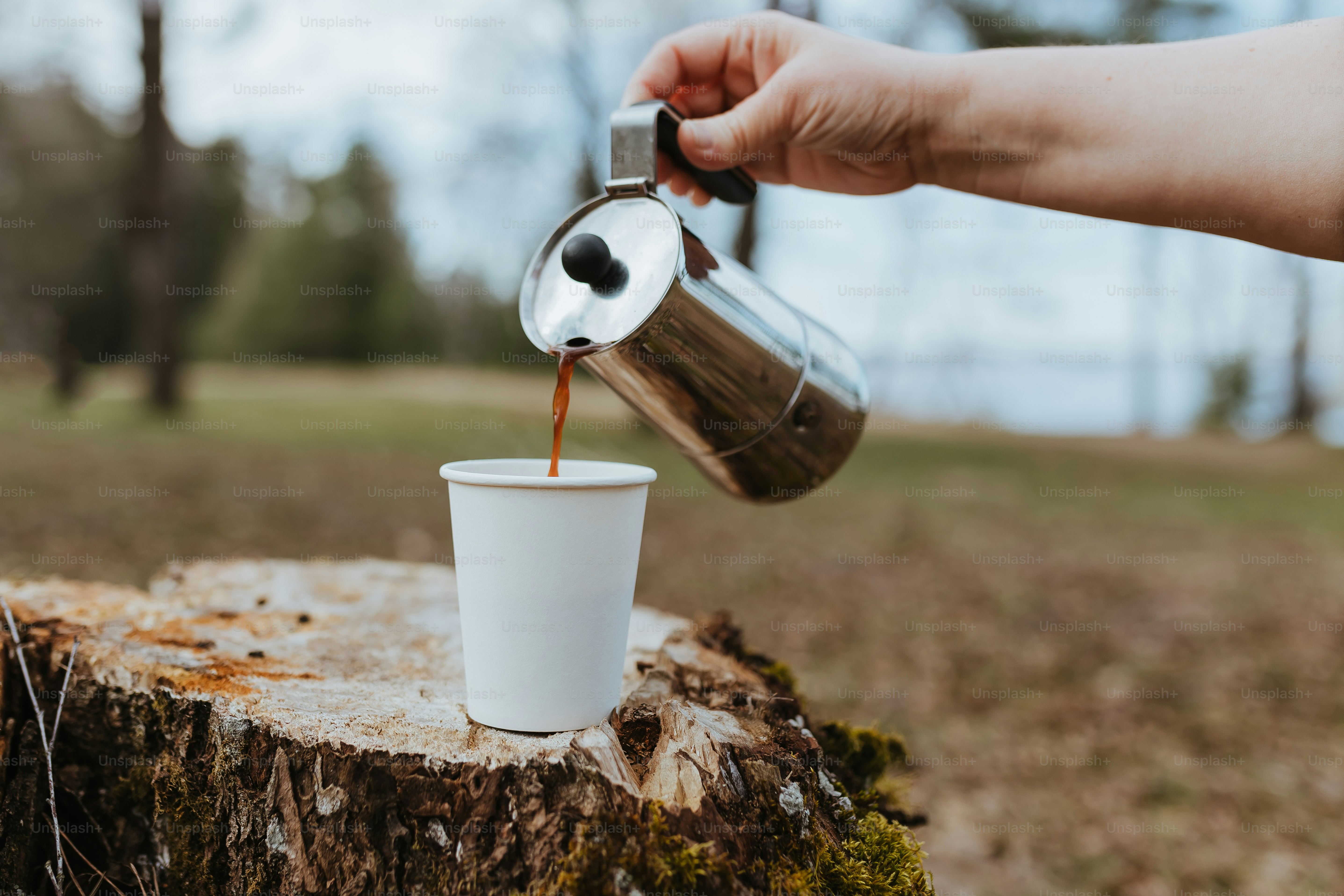 una persona versa il caffè in una tazza bianca