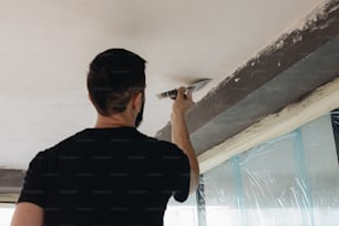 a man is painting a ceiling with a paint roller