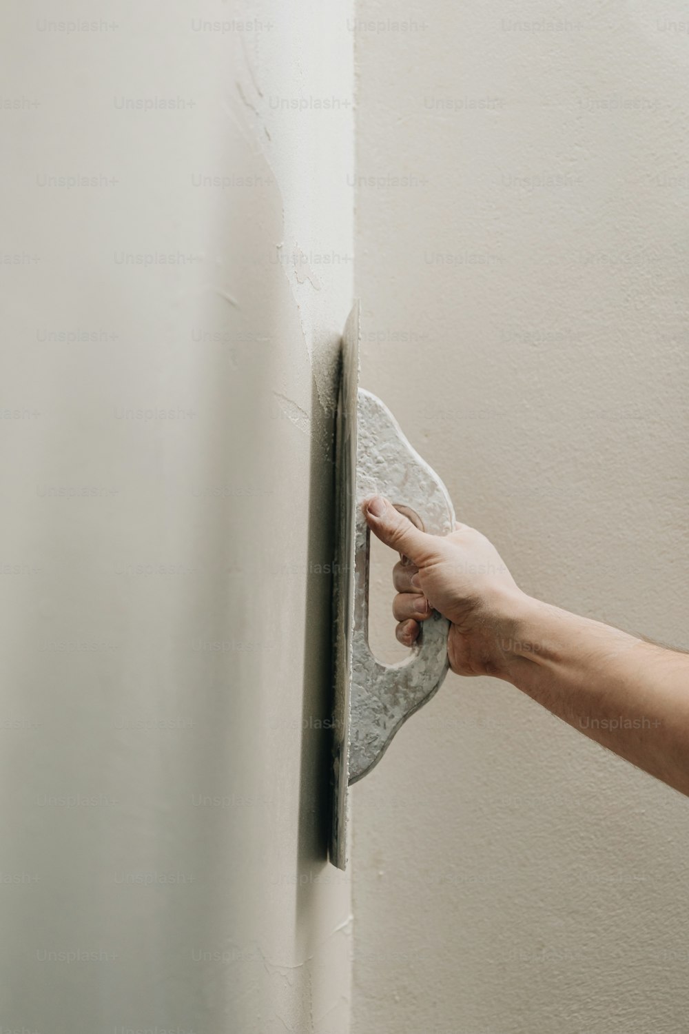 La mano de una persona sosteniendo una esponja en una pared