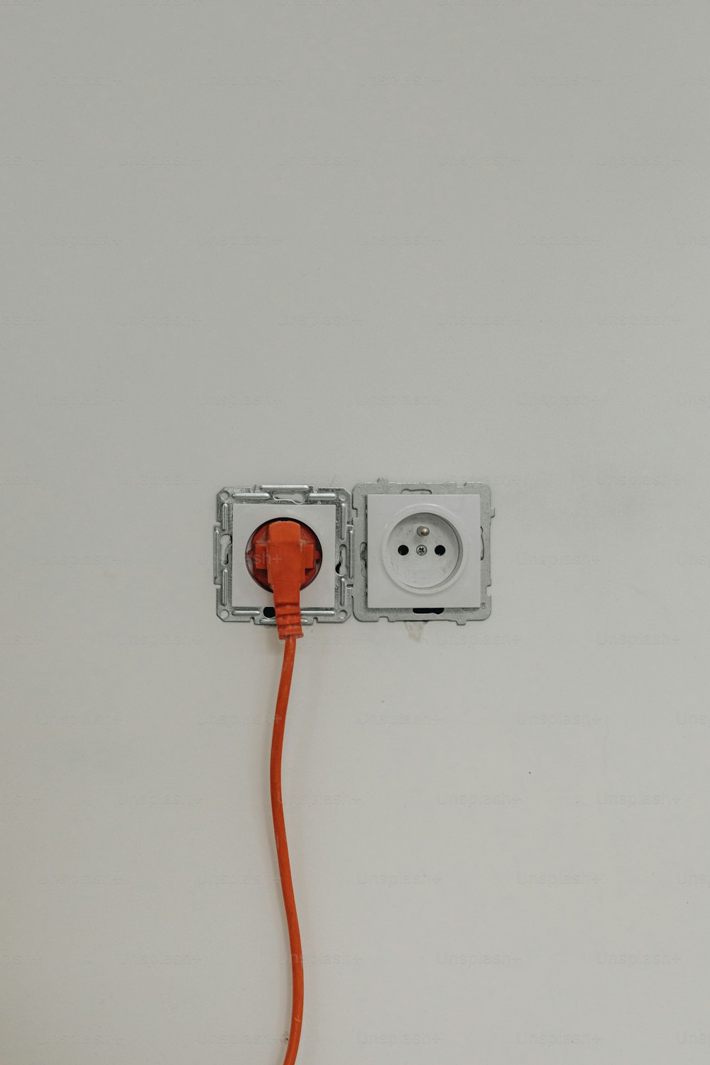 ein orangefarbenes Kabel, das an eine weiße Steckdose angeschlossen ist