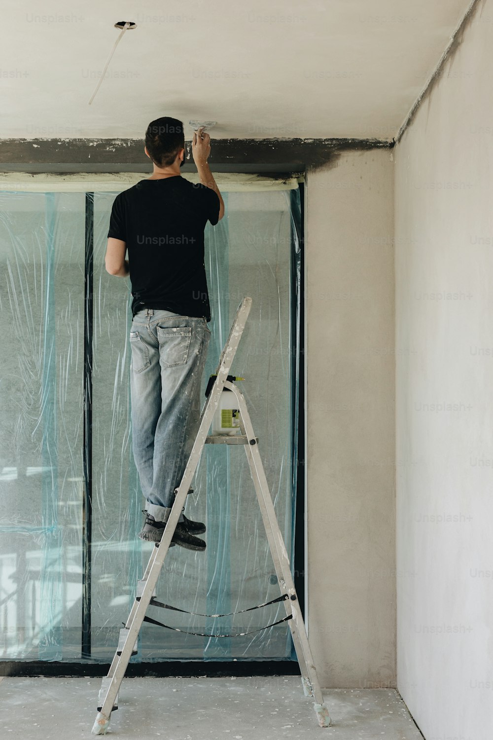 a man standing on a ladder painting a wall